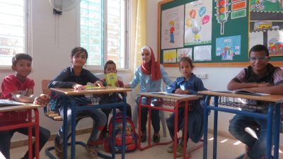 A teacher poses in classroom with young deaf students