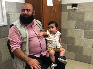 A father and his young son wait for the doctor, at Ahli Arab Hospital, Gaza City.