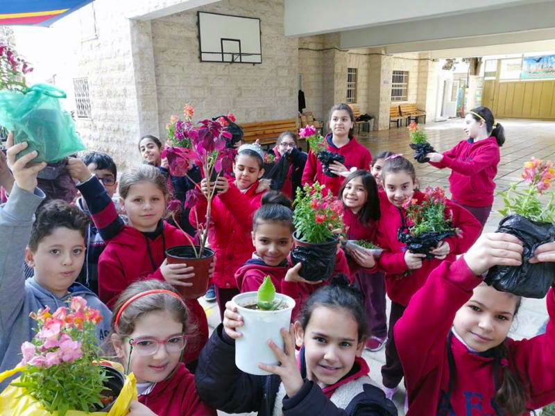 A photo of children showing off their plants in pots at Arab Episcopal School, Irbid, Jordan