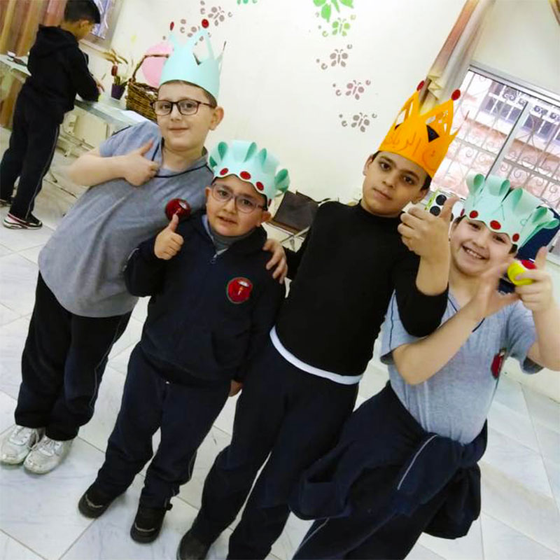 A photo of young students with thumbs up and fun hats on at Arab Episcopal School in Irbid, Jordan