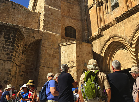 A photo of people gathered in front of an ancient chapel in Jerusalem