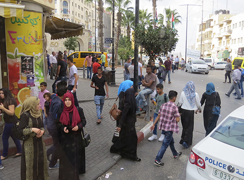 Many people walk on the sidewalk in a busy city scene