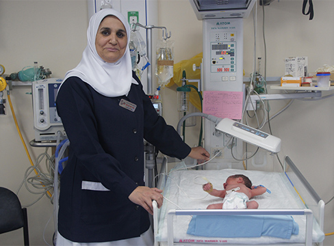 A nurse stands over a newborn baby cradle in the hospital